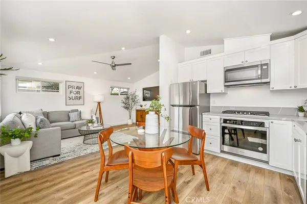 a kitchen with stainless steel appliances kitchen island granite countertop a dining table chairs refrigerator and sink