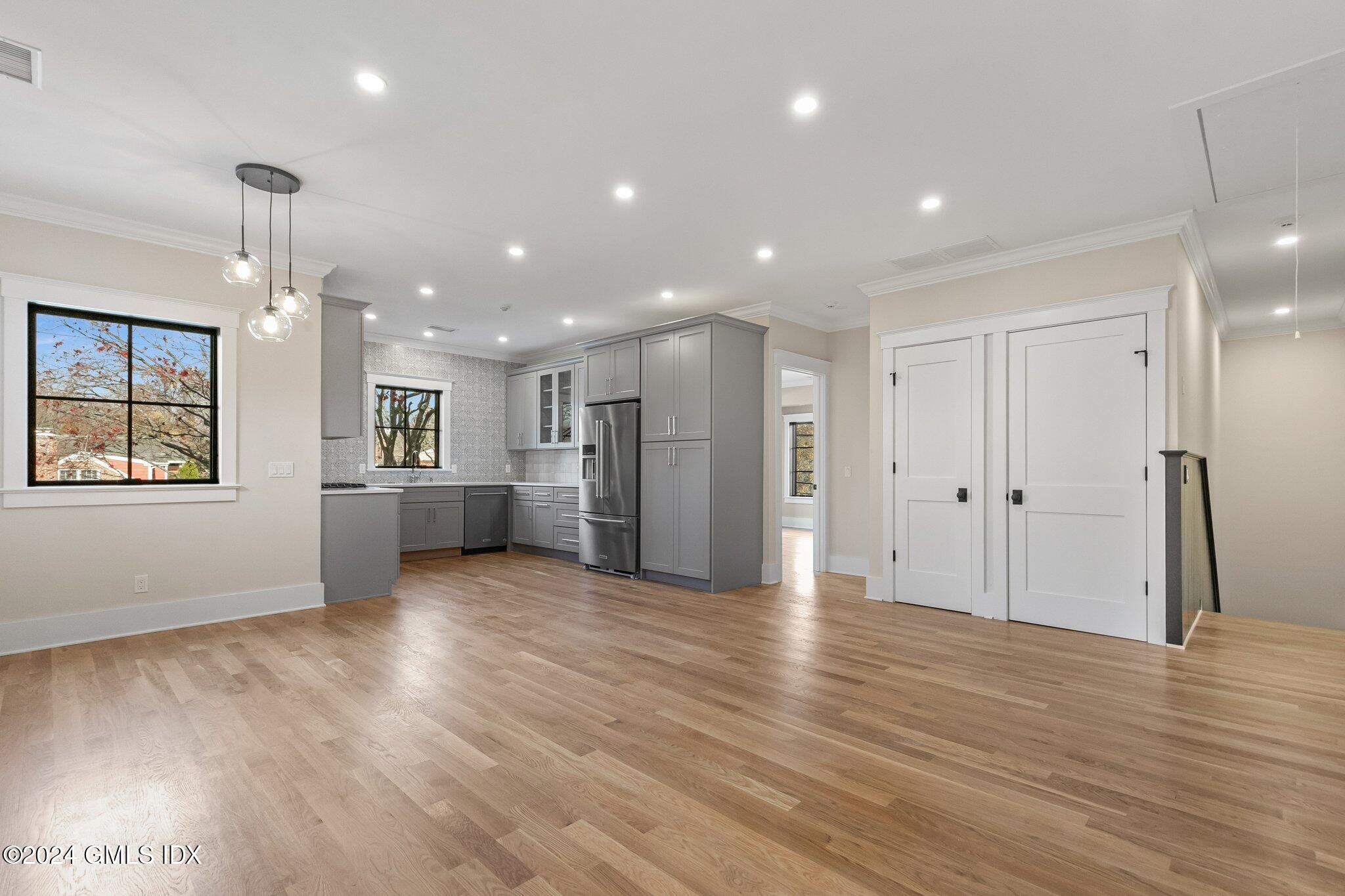 96 Weaver Street, Unit A Greenwich, CT 06831 - Photo 4 of 26 a view of an empty room with wooden floor kitchen view and windows