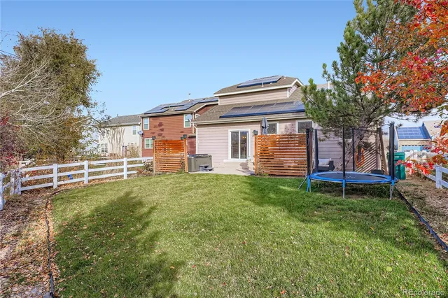 a backyard of a house with wooden fence and a large tree