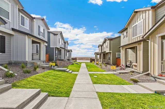 a view of a brick house with many windows plants and large tree