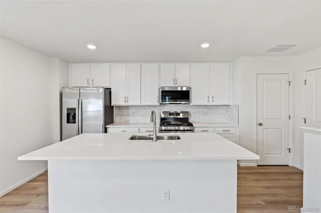 a kitchen with kitchen island a sink stainless steel appliances and white cabinets