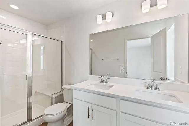 a bathroom with a sink toilet double vanity and shower