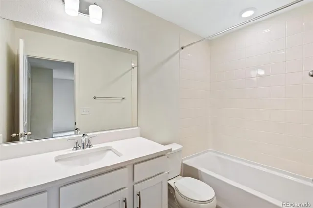 a bathroom with a granite countertop sink toilet a mirror and a bathtub
