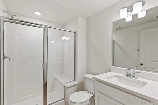a bathroom with a granite countertop sink toilet a mirror a vanity and shower