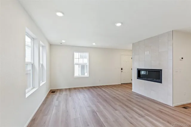 a view of a kitchen and an empty room with wooden floor and a window