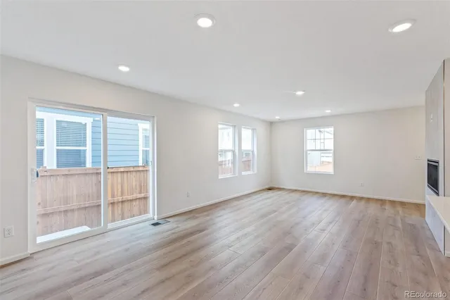 a view of an empty room with wooden floor and windows