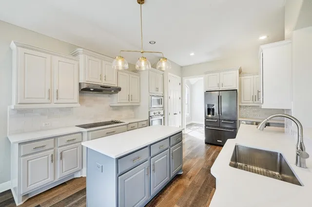 a kitchen with kitchen island granite countertop a sink appliances cabinets and a counter top space