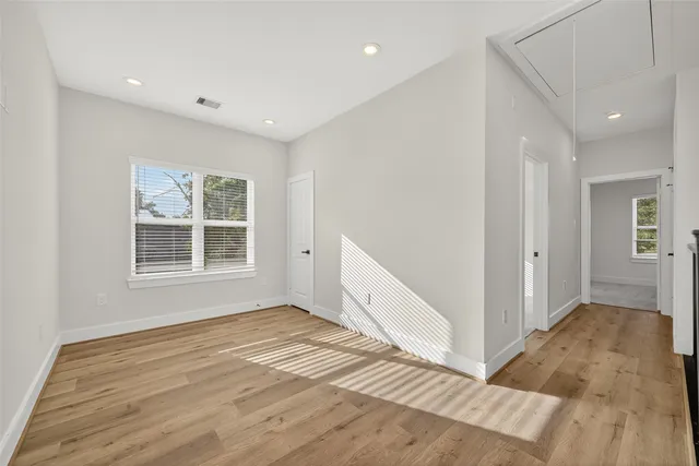 a view of an empty room with wooden floor and a window