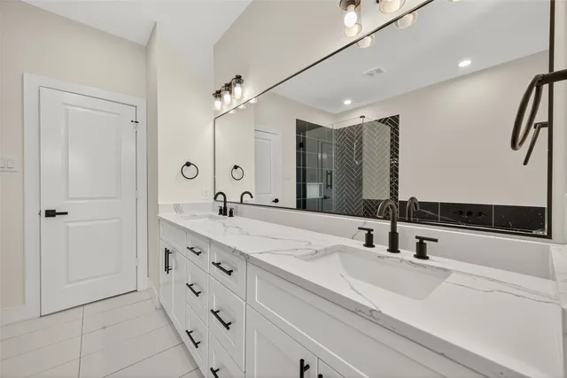 a spacious bathroom with a double vanity sink a large mirror and a bathtub