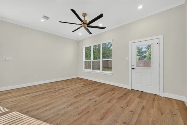an empty room with wooden floor a ceiling fan a fireplace and windows