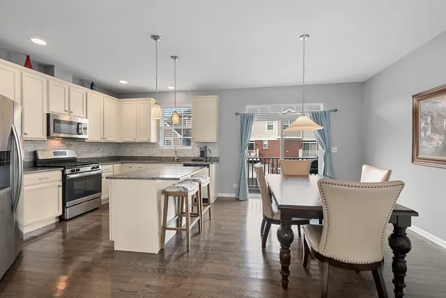 a kitchen with kitchen island a dining table chairs and white cabinets