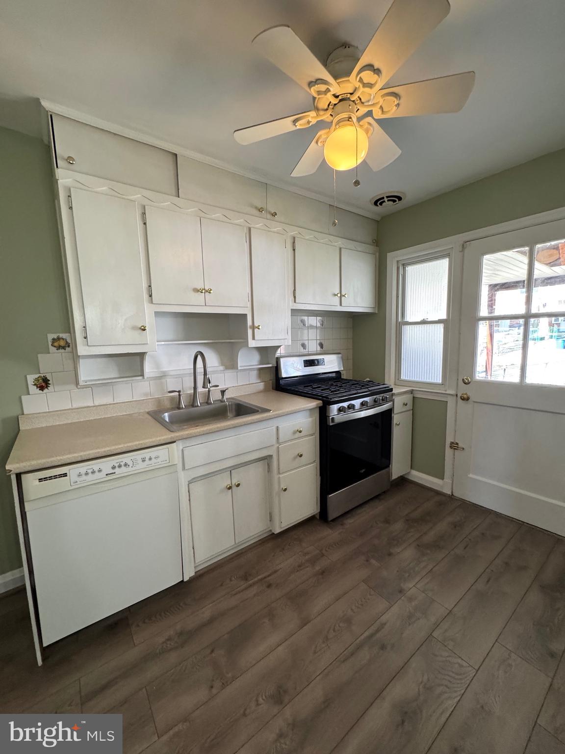 1052 Downton Road Baltimore, MD 21227 - Photo 12 of 55 a kitchen with a sink dishwasher a stove a refrigerator with cabinets and wooden floor