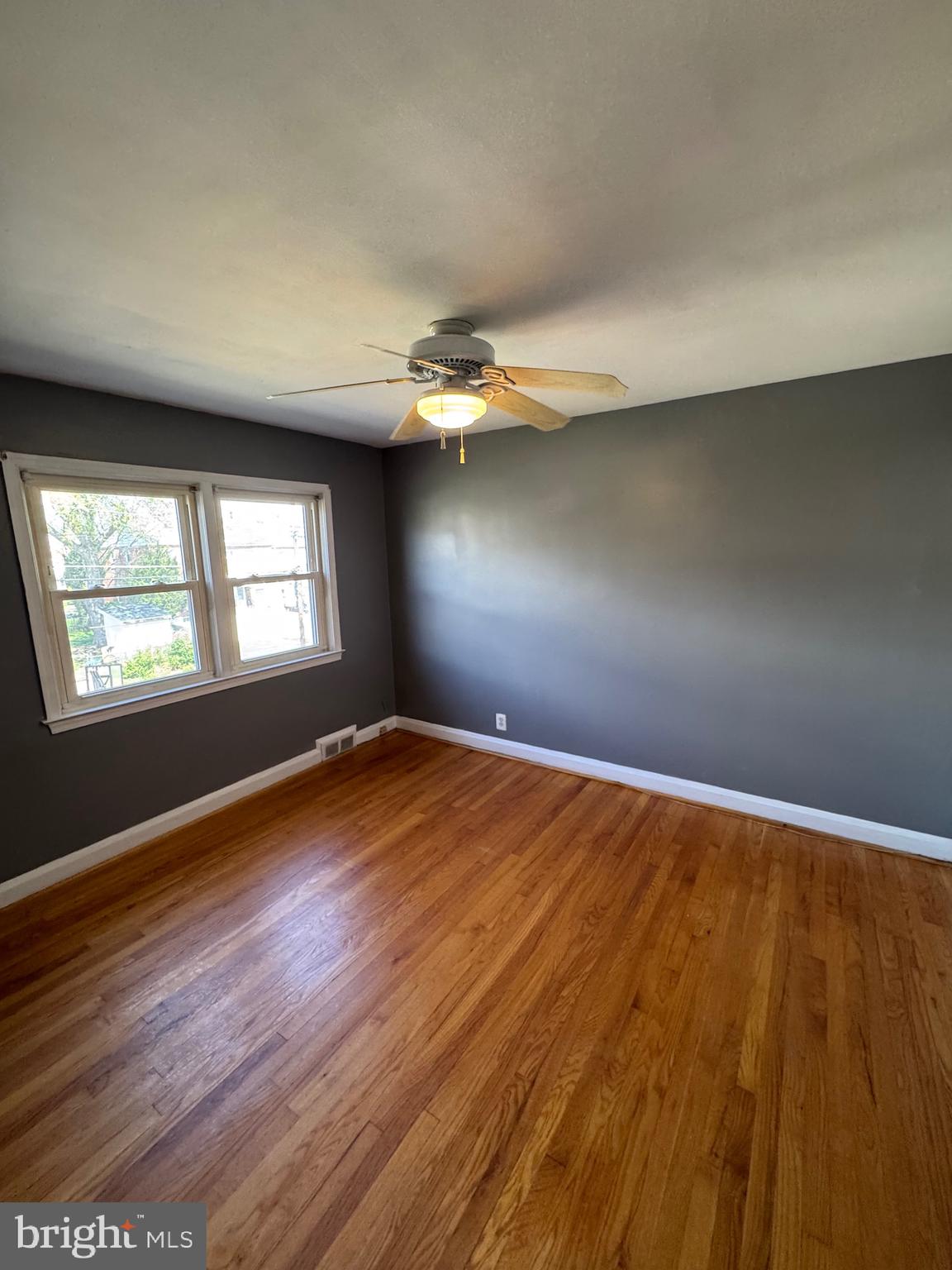 1052 Downton Road Baltimore, MD 21227 - Photo 21 of 55 an empty room with wooden floor and windows
