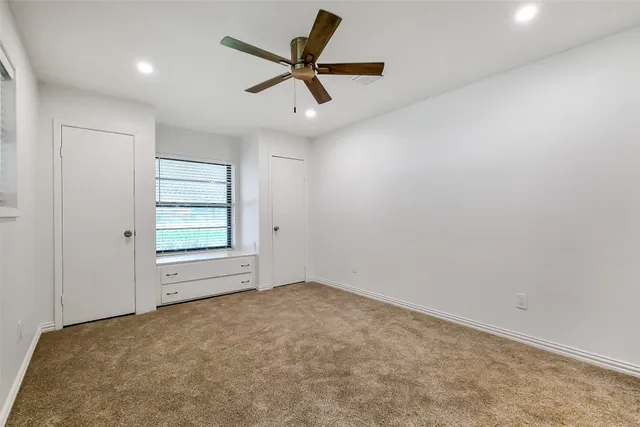 an empty room with a ceiling fan and window