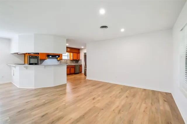 a view of a kitchen with wooden floor and an empty room