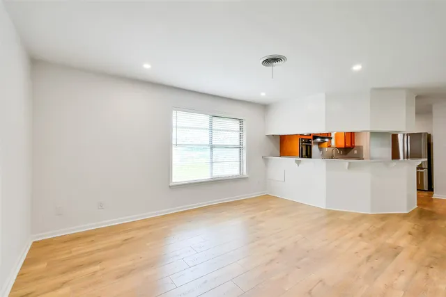 an empty room with a window and kitchen view