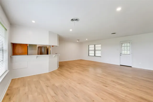 a view of empty room with wooden floor and windows