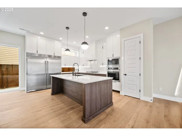 a large kitchen with stainless steel appliances kitchen island granite countertop a large counter top a stove a sink and a refrigerator