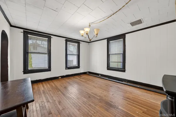 a view of an empty room with window and wooden floor