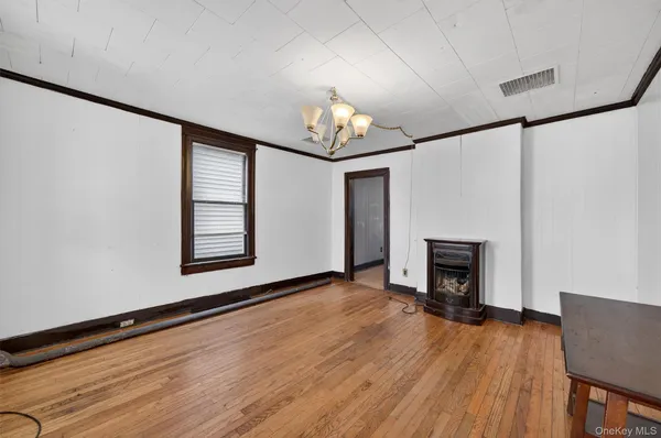 a view of an empty room with wooden floor fireplace and a window