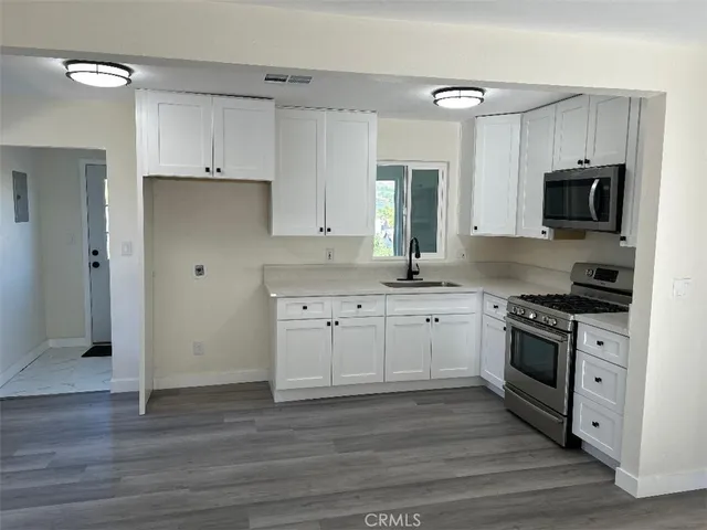 a kitchen with cabinets stainless steel appliances a sink and wooden floor