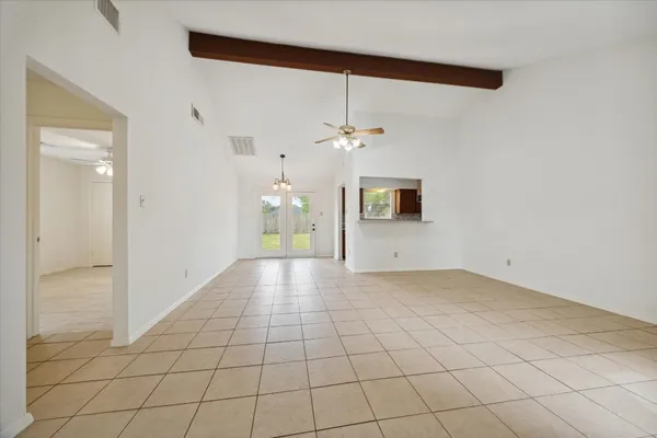 a view of an empty room and chandelier fan