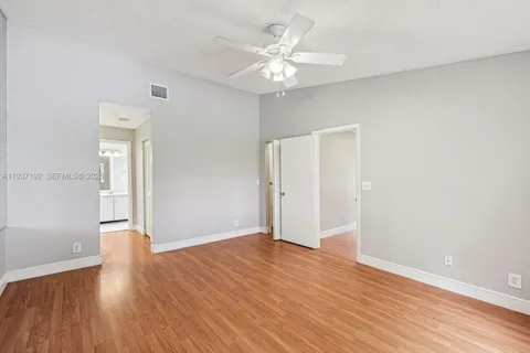 an empty room with wooden floor and a ceiling fan