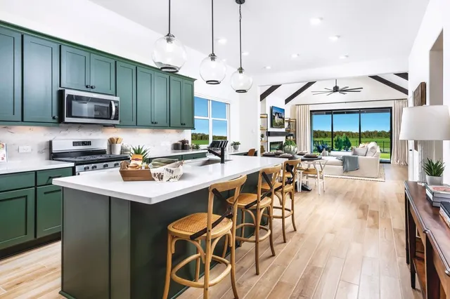 a kitchen with stainless steel appliances a table chairs refrigerator and cabinets