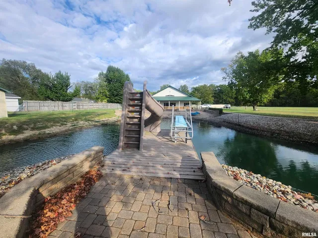 a view of a lake with a yard and large trees