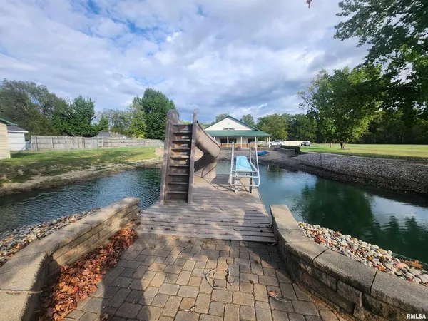 a view of a lake with a yard and large trees
