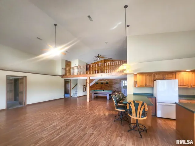 a kitchen with stainless steel appliances kitchen island granite countertop a table chairs sink and cabinets
