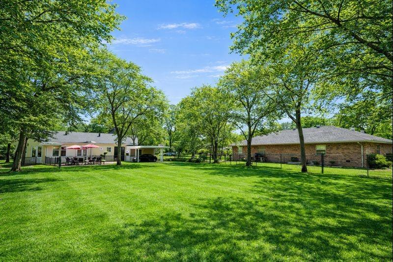 1505 Bonham Street Commerce, TX 75428 - Photo 33 of 39 Large lot with attached garage, carport, and outdoor cooking area. Grass and trees digitally enhanced to show seasonal potential