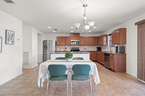 a view of a dining room with furniture a kitchen and chandelier