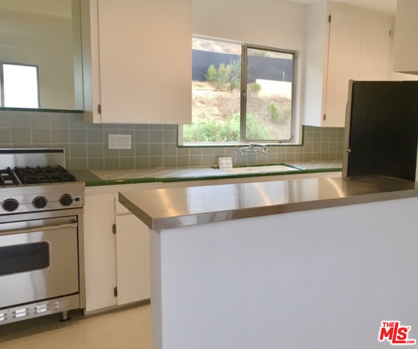 25121 Malibu Road Malibu, CA 90265 - Photo 8 of 16 a kitchen with granite countertop a sink a stove and a microwave