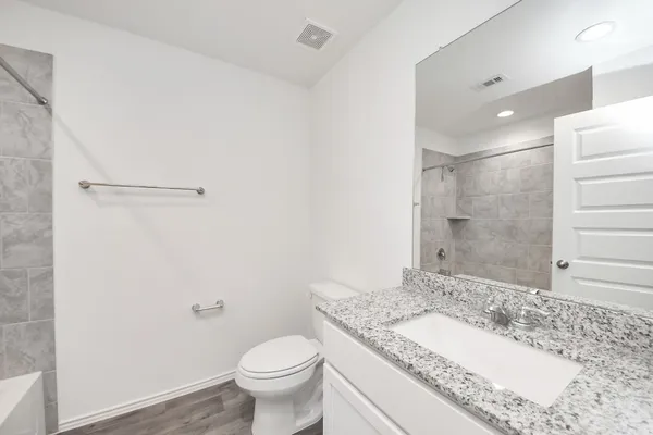 a bathroom with a granite countertop sink toilet and shower