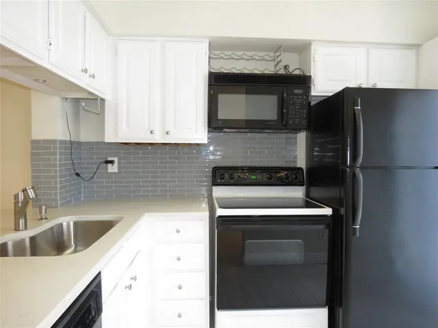 a kitchen with a refrigerator sink and cabinets