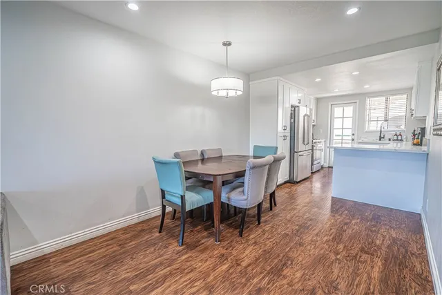 a dining room with wooden floor a chandelier a wooden table and chairs