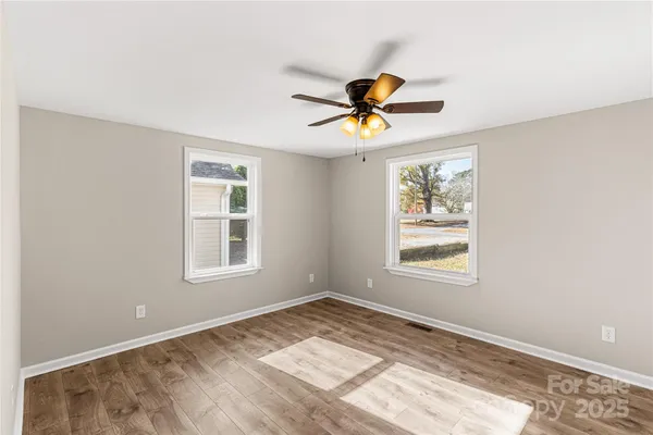 a view of empty room with wooden floor and ceiling fan
