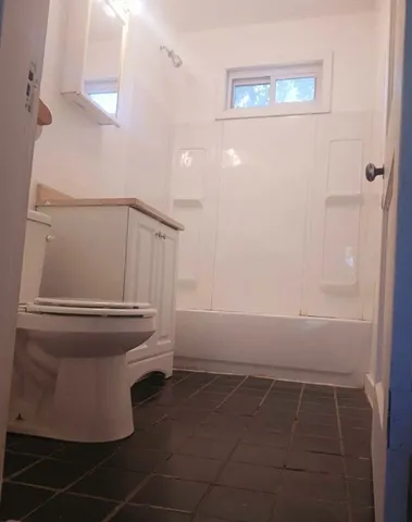 an empty room with wooden floor a ceiling fan and windows