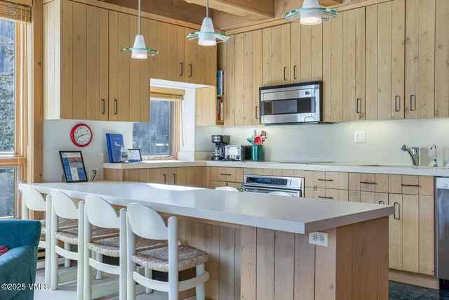 a kitchen with stainless steel appliances granite countertop a sink a microwave cabinets and a dining table