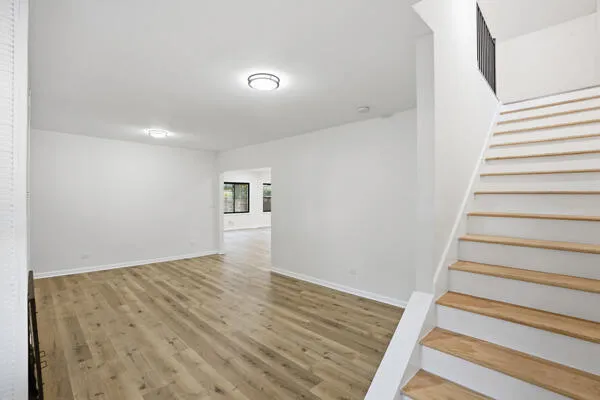 a view of an empty room with window and wooden floor