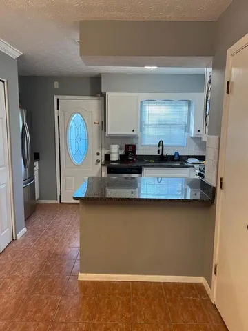 a kitchen with granite countertop a refrigerator a stove and a sink