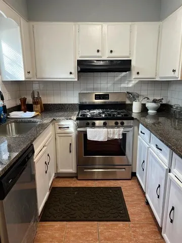 a kitchen with stainless steel appliances granite countertop a stove and a white cabinets