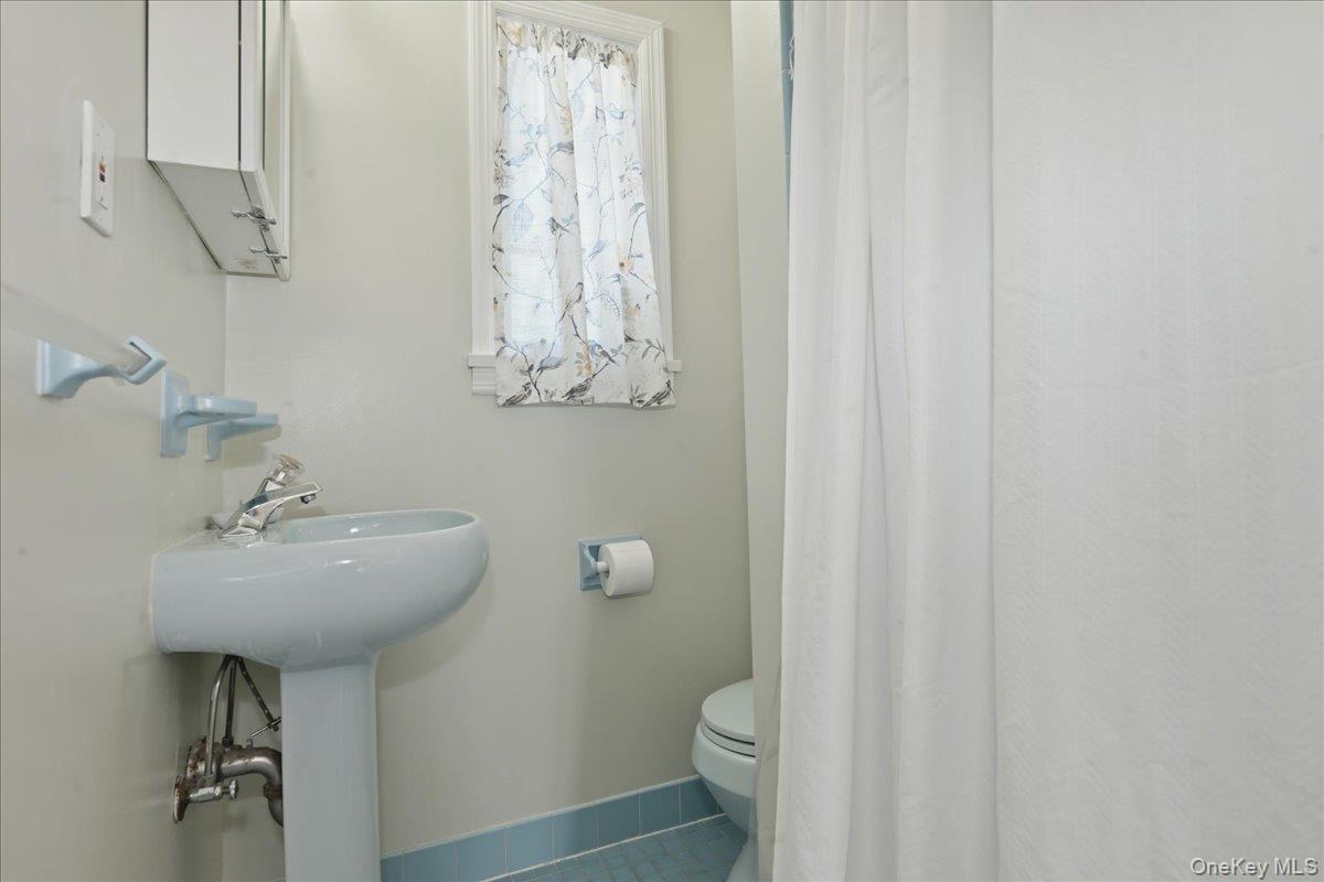 210 Clinton Road Garden City, NY 11530 - Photo 19 of 31 a bathroom with a sink a toilet and shower curtain