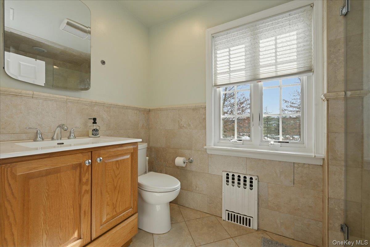 210 Clinton Road Garden City, NY 11530 - Photo 24 of 31 a bathroom with a sink a toilet and a window