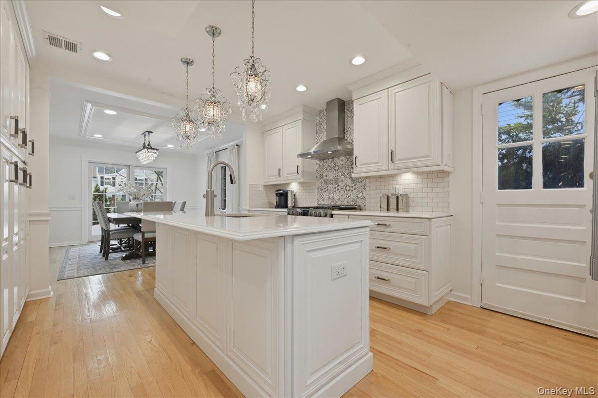 210 Clinton Road Garden City, NY 11530 - Photo 10 of 31 a large white kitchen with kitchen island a refrigerator a stove a sink dishwasher a oven and a dining table with wooden floor