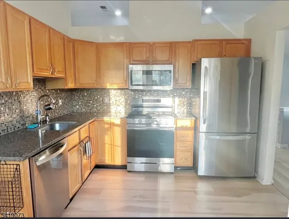 a kitchen with kitchen island granite countertop white cabinets and stainless steel appliances