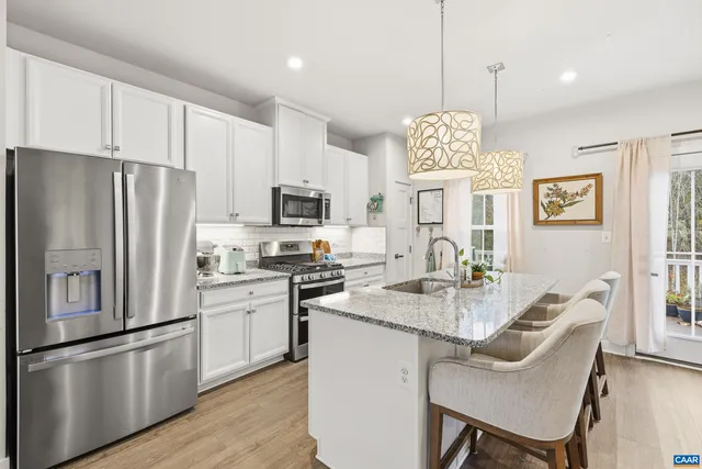 a kitchen with stainless steel appliances granite countertop a refrigerator a stove a sink dishwasher a dining table and chairs with wooden floor