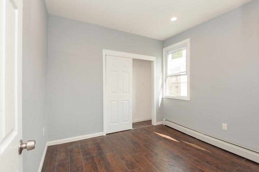 705 8th Street, Unit 2 Union City, NJ 07087 - Photo 18 of 19 an empty room with wooden floor and windows
