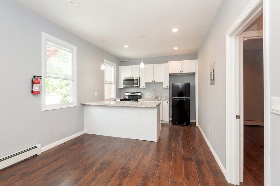 705 8th Street, Unit 2 Union City, NJ 07087 - Photo 4 of 19 a kitchen with white cabinets and wooden floor